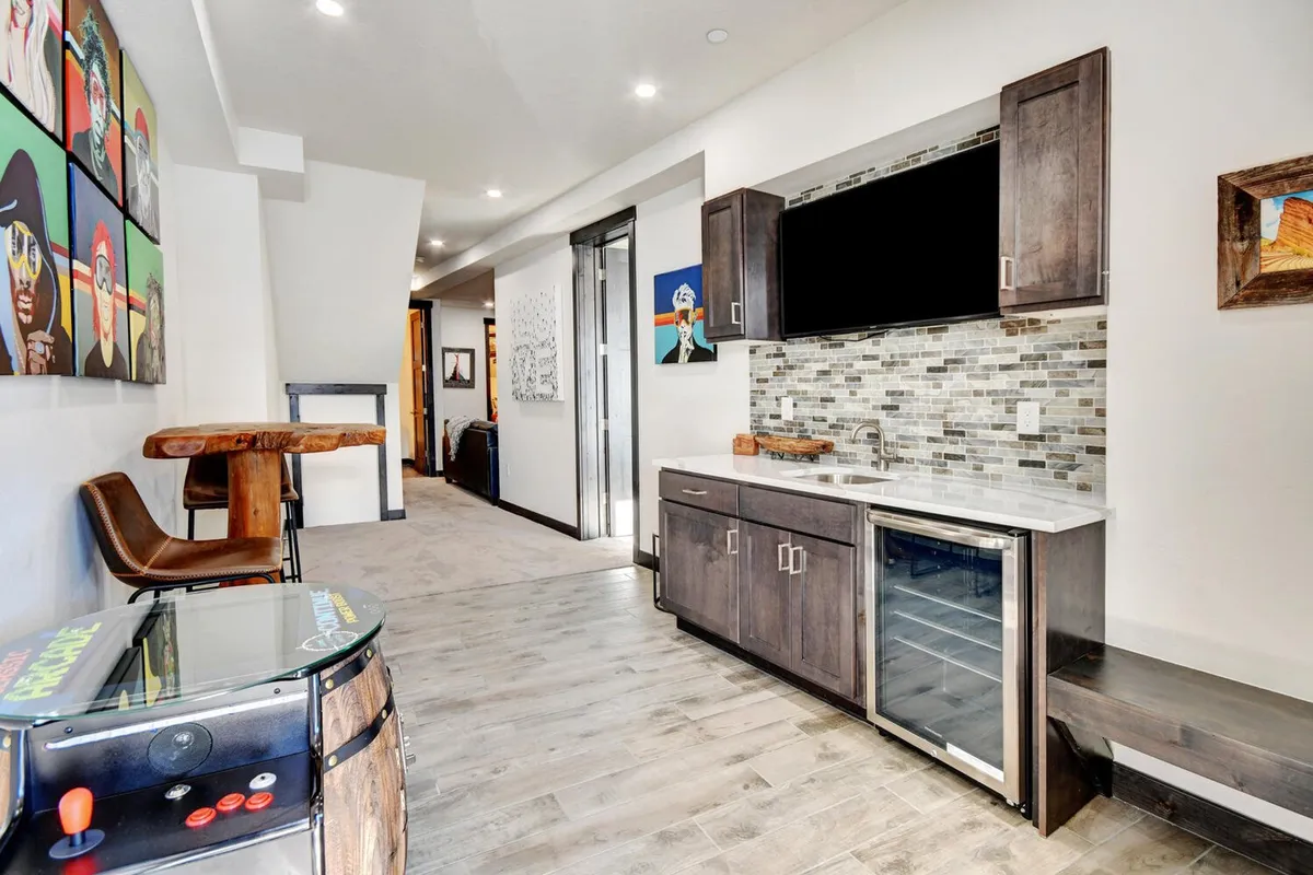 A chic bar area with stylish artwork on the walls and a functional kitchenette, creating a relaxed yet vibrant space for casual entertaining or toasting to the day’s adventures. Bar stools and an inviting setup signal a space ideal for drinks, snacks, or informal gatherings.