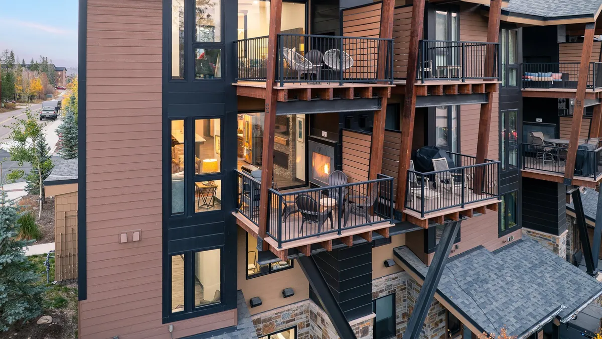 A welcoming exterior shot of the townhome with balconies, large windows, and a cozy outdoor fireplace. The inviting outdoor settings hint at group gatherings and the seamless connection between indoor comfort and outdoor exploration.