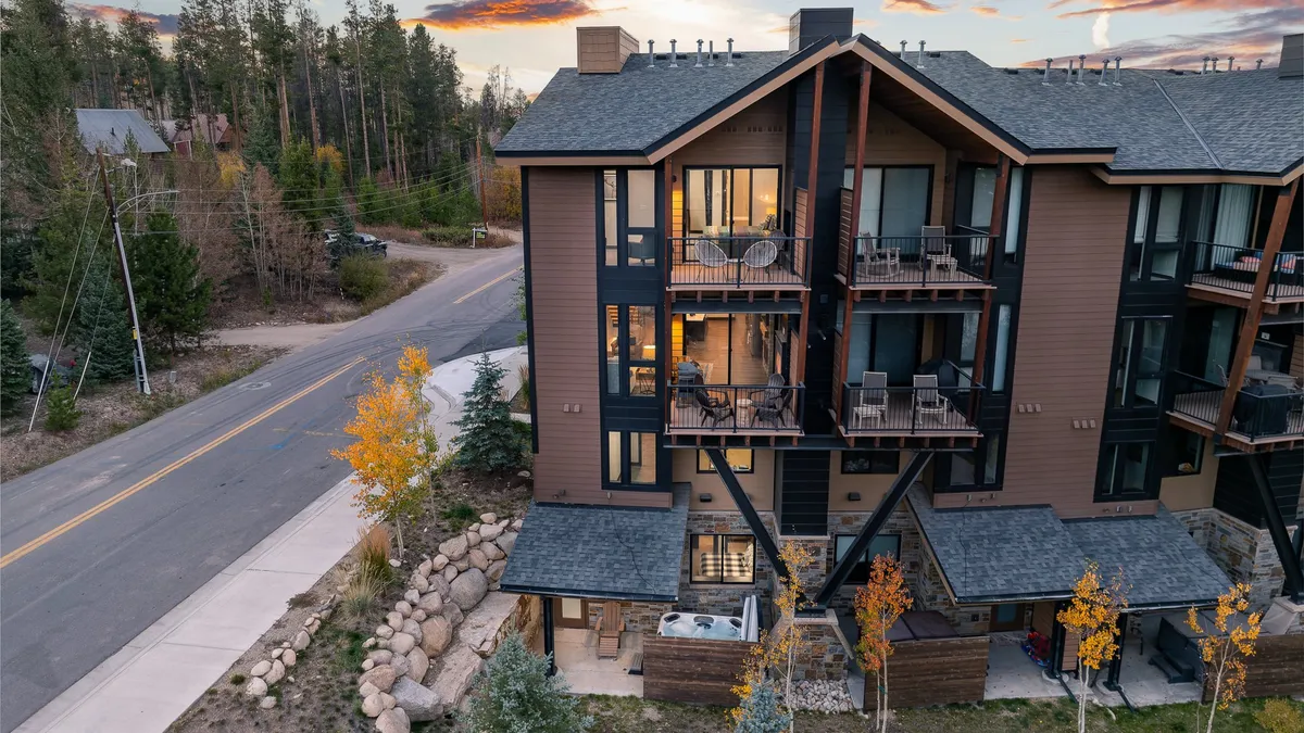 The modern exterior of the townhome is highlighted by stylish balconies with comfortable seating, surrounded by tranquil trees. The image conveys an atmosphere of serenity and exclusivity, while also alluding to the premium amenities available for relaxation and connection with nature.