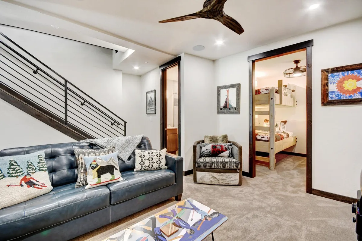 A cozy family zone with a sofa adorned with colorful pillows, visible bunk beds in the background, and playful artwork. The open layout and inviting design make it suitable for both adult relaxation and children’s activities, such as story time or games.